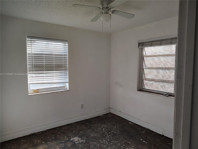 empty room with a textured ceiling, a wealth of natural light, and ceiling fan