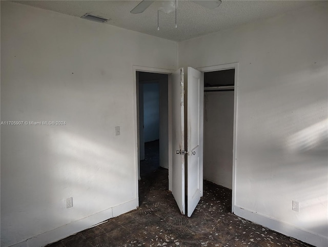 unfurnished bedroom with ceiling fan, a textured ceiling, and a closet