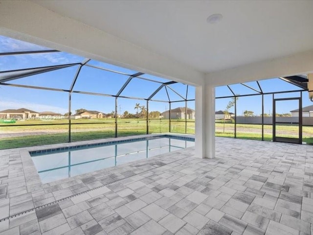 view of swimming pool featuring a lawn, glass enclosure, and a patio area