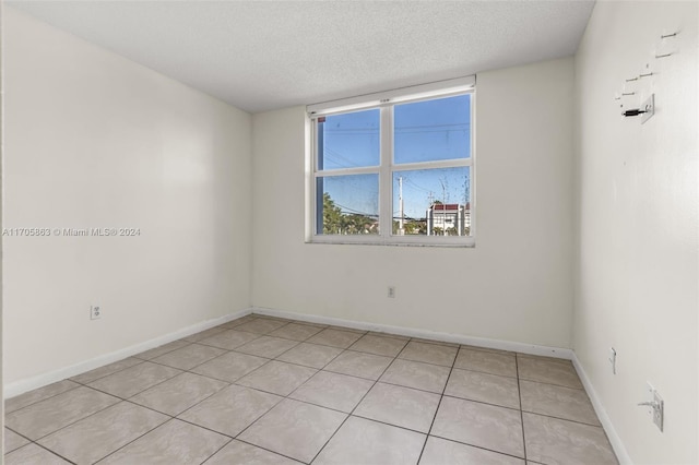 spare room with a textured ceiling and light tile patterned flooring