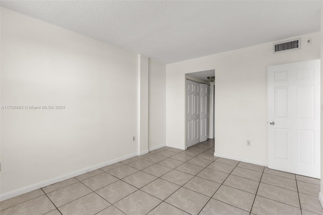 spare room featuring light tile patterned floors and a textured ceiling