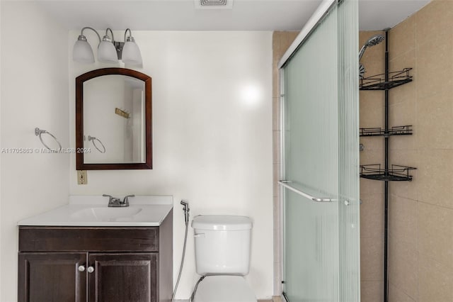 bathroom featuring vanity, toilet, and a shower with door