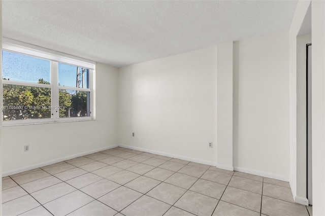 empty room with light tile patterned flooring and a textured ceiling