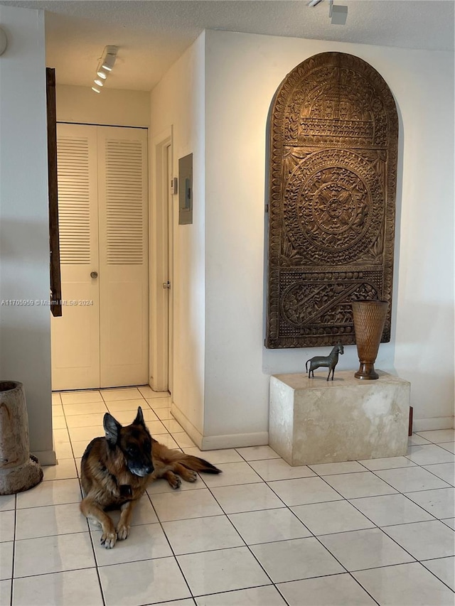 corridor featuring light tile patterned floors, a textured ceiling, and electric panel