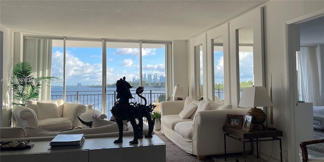 living room with floor to ceiling windows, a water view, and a textured ceiling