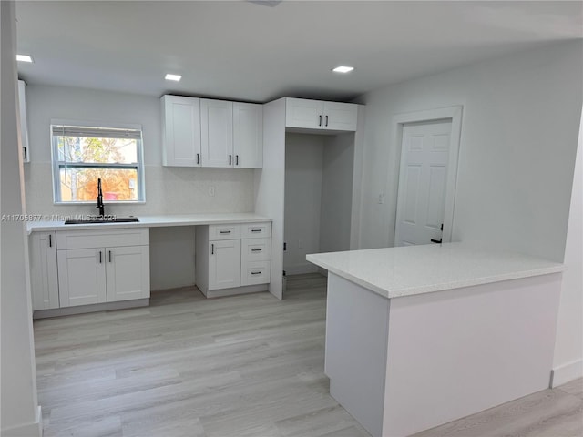 kitchen with decorative backsplash, kitchen peninsula, sink, white cabinets, and light hardwood / wood-style floors