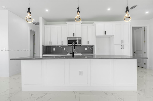 kitchen featuring white cabinetry, a kitchen island with sink, and hanging light fixtures