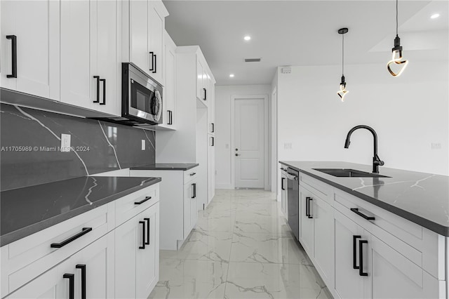 kitchen featuring decorative light fixtures, stainless steel appliances, dark stone countertops, and sink