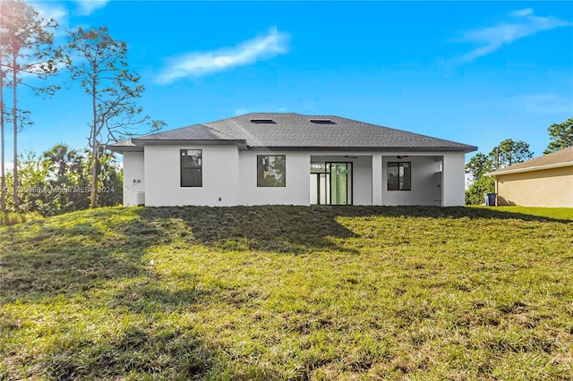 rear view of property with a lawn and ceiling fan