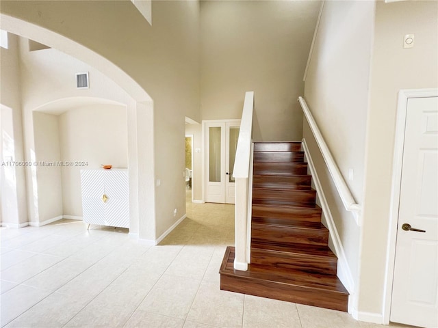 staircase featuring tile patterned floors and a high ceiling