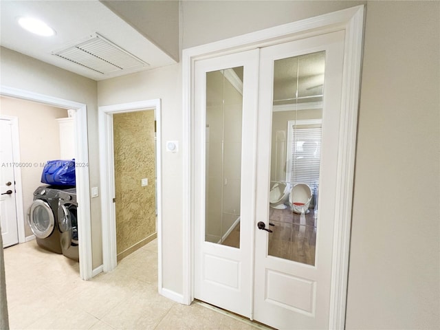 interior space with light tile patterned flooring, washing machine and dryer, ornamental molding, and french doors