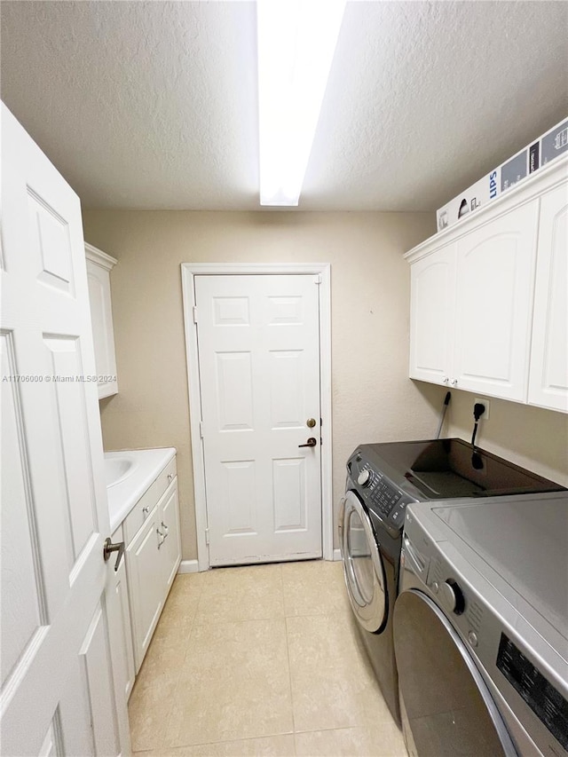 laundry room with cabinets, washing machine and dryer, light tile patterned floors, and a textured ceiling