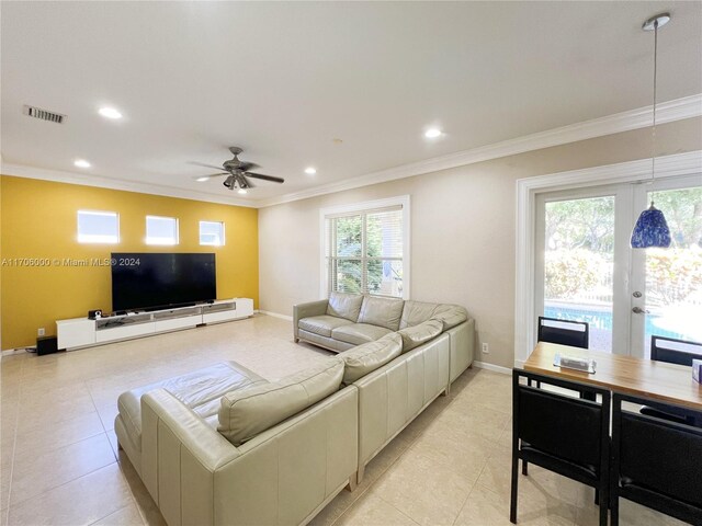 tiled living room featuring ceiling fan, crown molding, and french doors