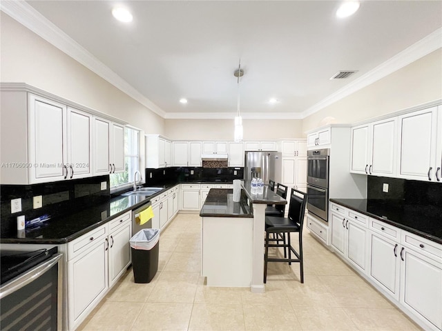 kitchen featuring white cabinetry, stainless steel appliances, tasteful backsplash, a breakfast bar area, and a kitchen island