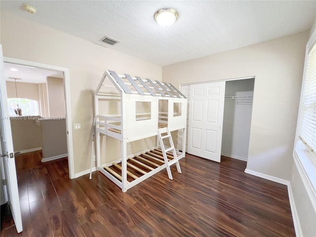 bedroom featuring a textured ceiling, dark wood-type flooring, and a closet