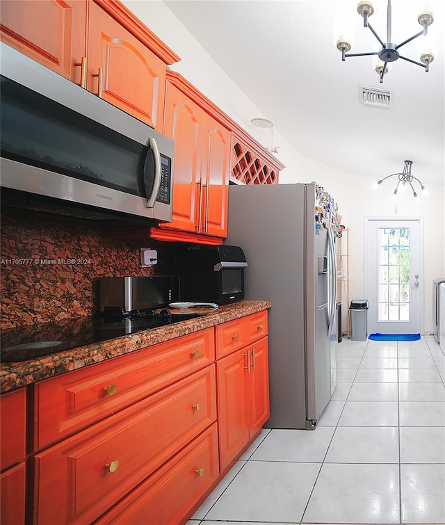 kitchen featuring tasteful backsplash, black electric cooktop, a notable chandelier, dark stone countertops, and light tile patterned flooring