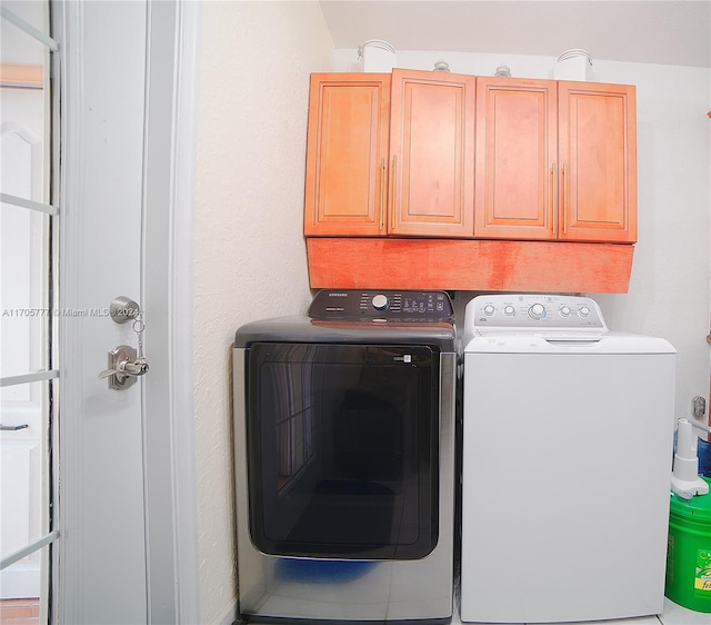 clothes washing area with cabinets and washer and clothes dryer