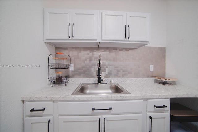 kitchen featuring light stone counters, tasteful backsplash, white cabinetry, and sink