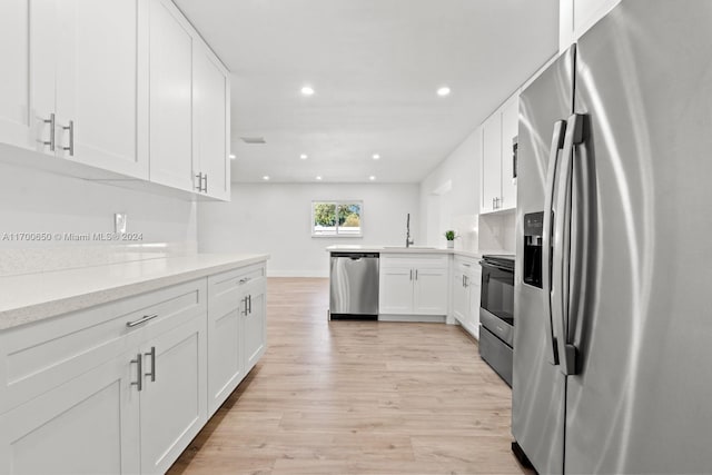 kitchen with sink, light hardwood / wood-style flooring, appliances with stainless steel finishes, white cabinetry, and kitchen peninsula