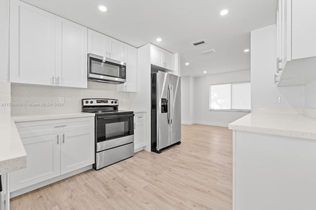 kitchen with light stone countertops, white cabinetry, stainless steel appliances, and light hardwood / wood-style floors