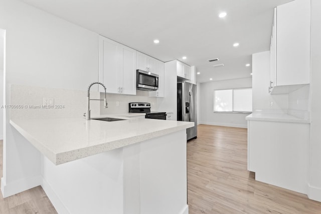 kitchen with white cabinetry, sink, kitchen peninsula, light hardwood / wood-style floors, and appliances with stainless steel finishes