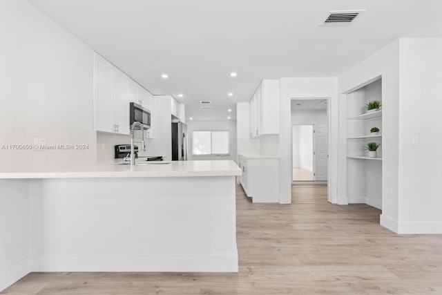 kitchen featuring kitchen peninsula, light hardwood / wood-style flooring, white cabinets, and appliances with stainless steel finishes