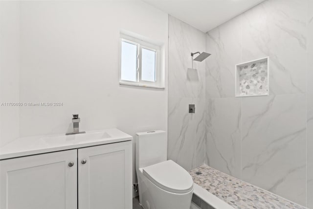 bathroom with vanity, toilet, and a tile shower