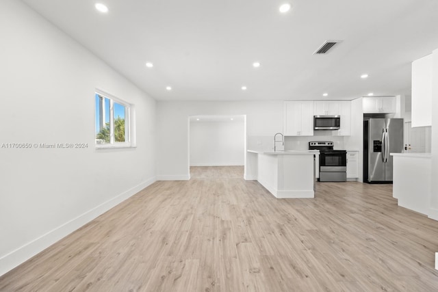 kitchen with a kitchen island with sink, sink, light hardwood / wood-style flooring, white cabinetry, and stainless steel appliances