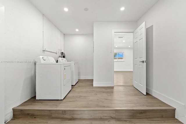 laundry area featuring washing machine and clothes dryer and light wood-type flooring