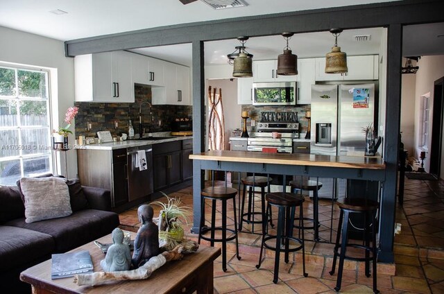 kitchen featuring stainless steel appliances, tasteful backsplash, sink, and white cabinetry