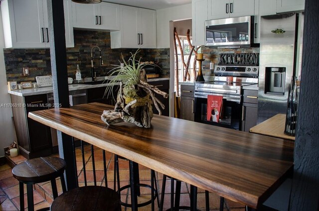 kitchen featuring stainless steel appliances, white cabinets, and backsplash