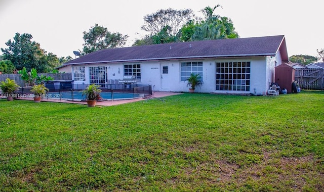 rear view of property featuring a pool, a lawn, and a patio area