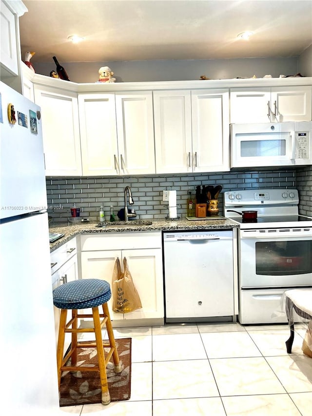 kitchen with white cabinets, white appliances, stone countertops, and sink