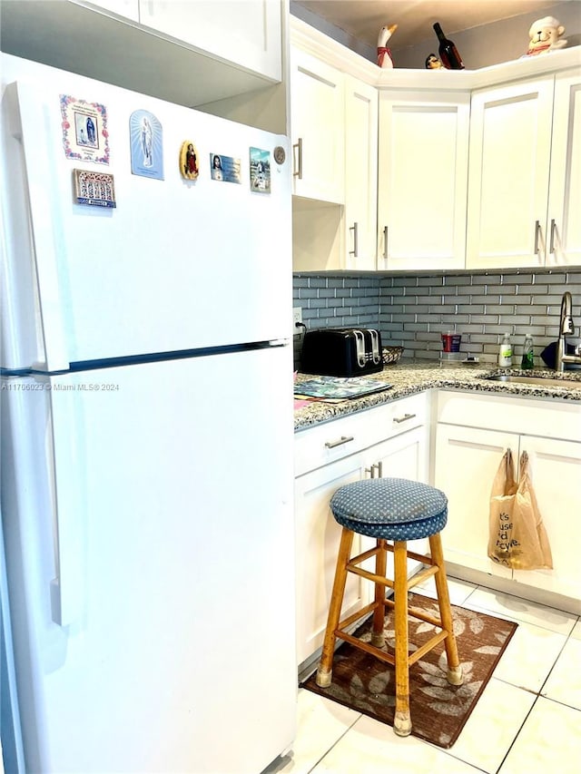 kitchen with backsplash, white cabinetry, sink, and white fridge