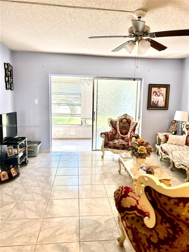 living room featuring light tile patterned floors, a textured ceiling, and ceiling fan