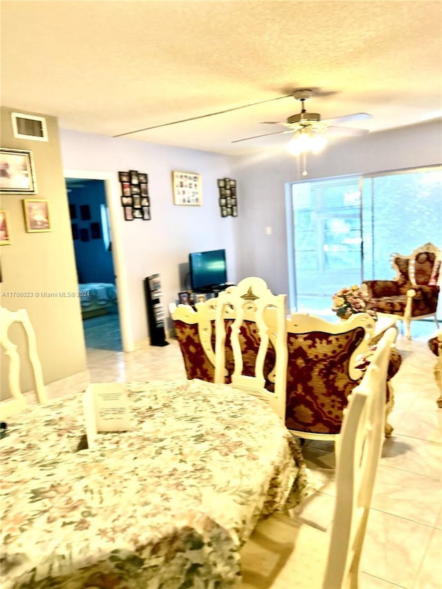 dining area featuring a textured ceiling, ceiling fan, and light tile patterned flooring