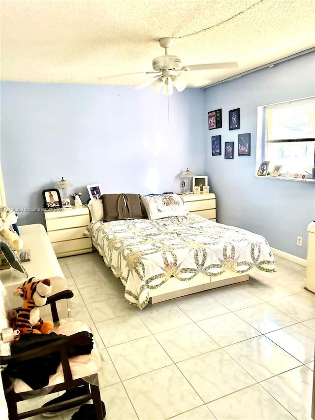 bedroom featuring ceiling fan, light tile patterned flooring, and a textured ceiling