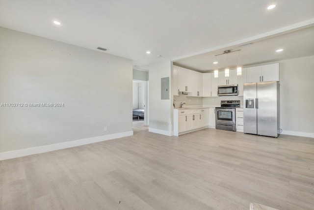 unfurnished living room featuring sink, electric panel, and light hardwood / wood-style flooring