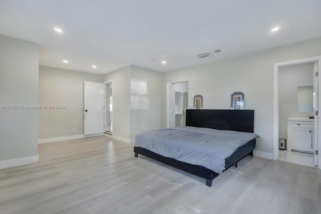 bedroom with connected bathroom and light hardwood / wood-style floors