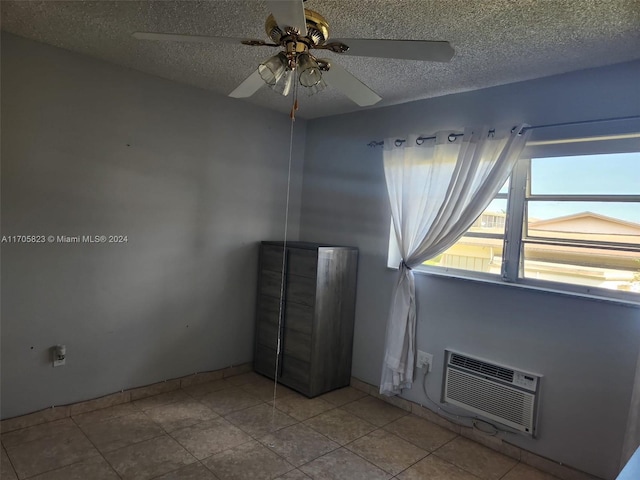 tiled empty room featuring a wall mounted air conditioner, a textured ceiling, and ceiling fan