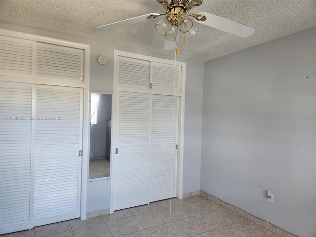 unfurnished bedroom featuring light tile patterned floors, a textured ceiling, a closet, and ceiling fan