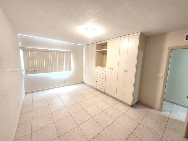 unfurnished bedroom with a closet, light tile patterned flooring, and a textured ceiling