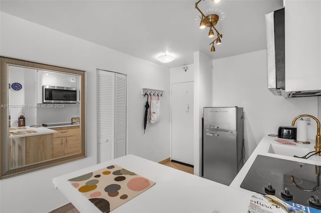 kitchen with cooktop, sink, white cabinets, and light hardwood / wood-style floors