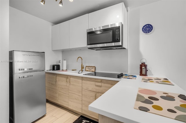 kitchen with white cabinets, light hardwood / wood-style floors, and stainless steel appliances