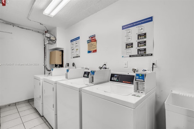 laundry area featuring independent washer and dryer, a textured ceiling, and light tile patterned flooring