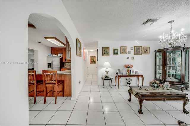 hallway featuring light tile patterned floors, a textured ceiling, and an inviting chandelier