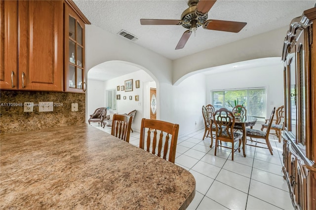 dining space featuring ceiling fan, light tile patterned flooring, and a textured ceiling