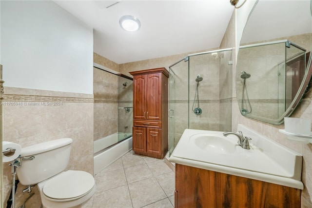 full bathroom featuring vanity, tile patterned floors, combined bath / shower with glass door, toilet, and tile walls