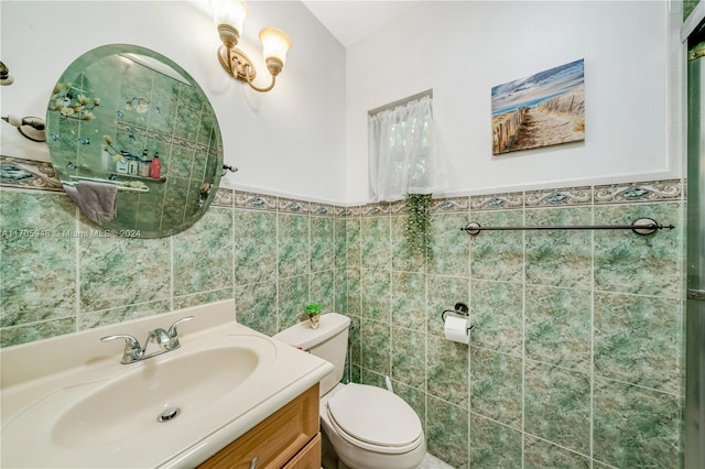 bathroom featuring vanity, toilet, and tile walls