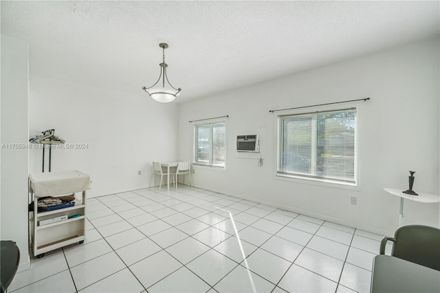 interior space with an AC wall unit, light tile patterned floors, and a textured ceiling